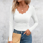 The Scalloped Long-Sleeve Top is a feminine and versatile wardrobe essential featuring a soft white colour and a beautifully curved scalloped neckline. Its fitted silhouette creates a flattering look, while the long sleeves make it perfect for layering and everyday wear. The delicate scalloped neckline adds a pretty, elegant detail that sets this top apart from a classic basic. The soft, simple design makes it easy to style with your favourite jeans, trousers or skirts, whether you're dressing casually or creating a more polished outfit. Pair the Scalloped Long-Sleeve Top with denim and sneakers for an effortless everyday look, or dress it up with tailored trousers, accessories and boots or heels. Its classic white colour makes it a versatile piece that can easily become a favourite in your wardrobe. Product Features - Classic white colour - Feminine scalloped neckline - Long sleeves - Flattering fitted silhouette - Simple and versatile design - Easy to layer - Perfect for casual and smart-casual outfits - Easy to pair with jeans, trousers or skirts The Scalloped Long-Sleeve Top is a timeless addition to any wardrobe, combining a classic neutral colour with a feminine neckline for effortless everyday style.