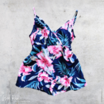 Baby Tropical Navy Romper featuring a navy background, vibrant pink tropical flowers, blue foliage, delicate shoulder straps and a V-shaped neckline.