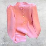 Pink Gold Button Jersey featuring a soft pink knit design, long sleeves, puffed shoulders, ribbed cuffs and hem, and elegant gold-tone front buttons.