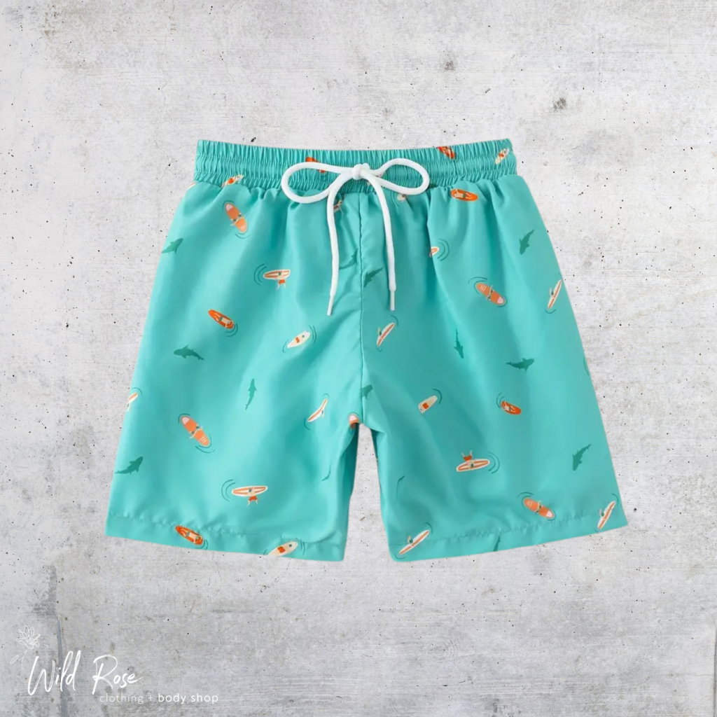 Ocean Surfer Boys’ Swim Shorts in turquoise with a playful ocean-inspired print, elastic waistband and white drawstring.