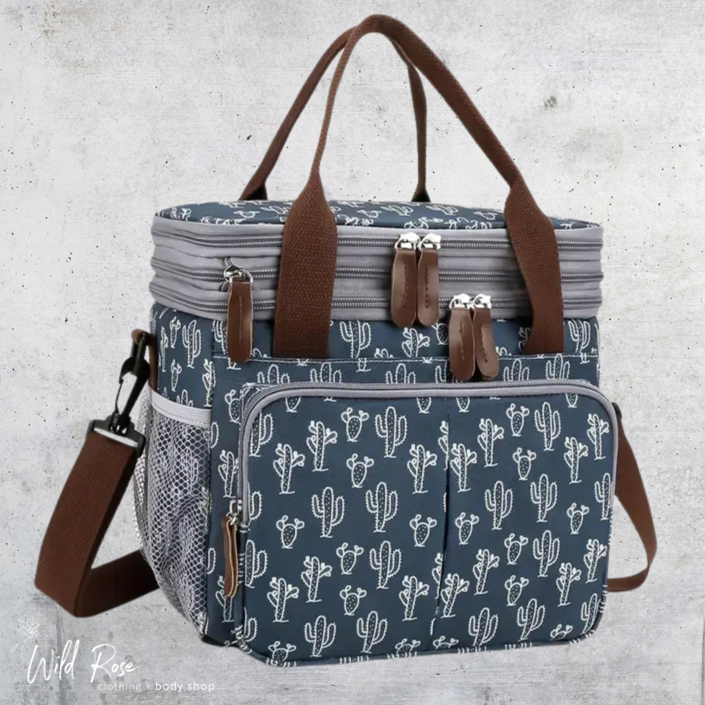 Cactus Print Cooler Bag featuring a deep blue background, white cactus pattern, brown handles, multiple zippered compartments and an adjustable shoulder strap.