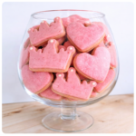 Pink large princess biscuits decorated with crowns and hearts, displayed in a glass bowl for birthdays and special celebrations at The Cupcake Lounge.