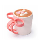 Party Bites Hot Chocolate topped with marshmallows in a white mug with a pink bow-shaped handle on a white background.