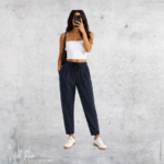 Woman wearing navy long loose ankle cuff pants with a relaxed fit, elasticated waistband and casual white sneakers.