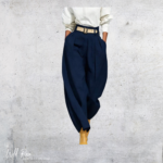 Woman wearing navy high-waisted pleated trousers with a relaxed tapered fit, styled with a white long-sleeve top.